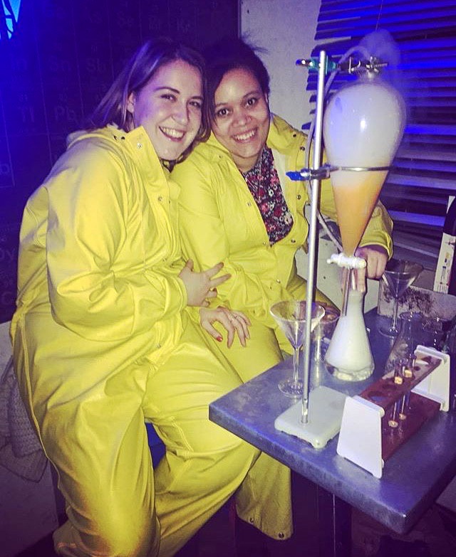 Unique Themed Cocktail Bars in London - Two girls dressed in yellow jumpsuits drinking cocktails