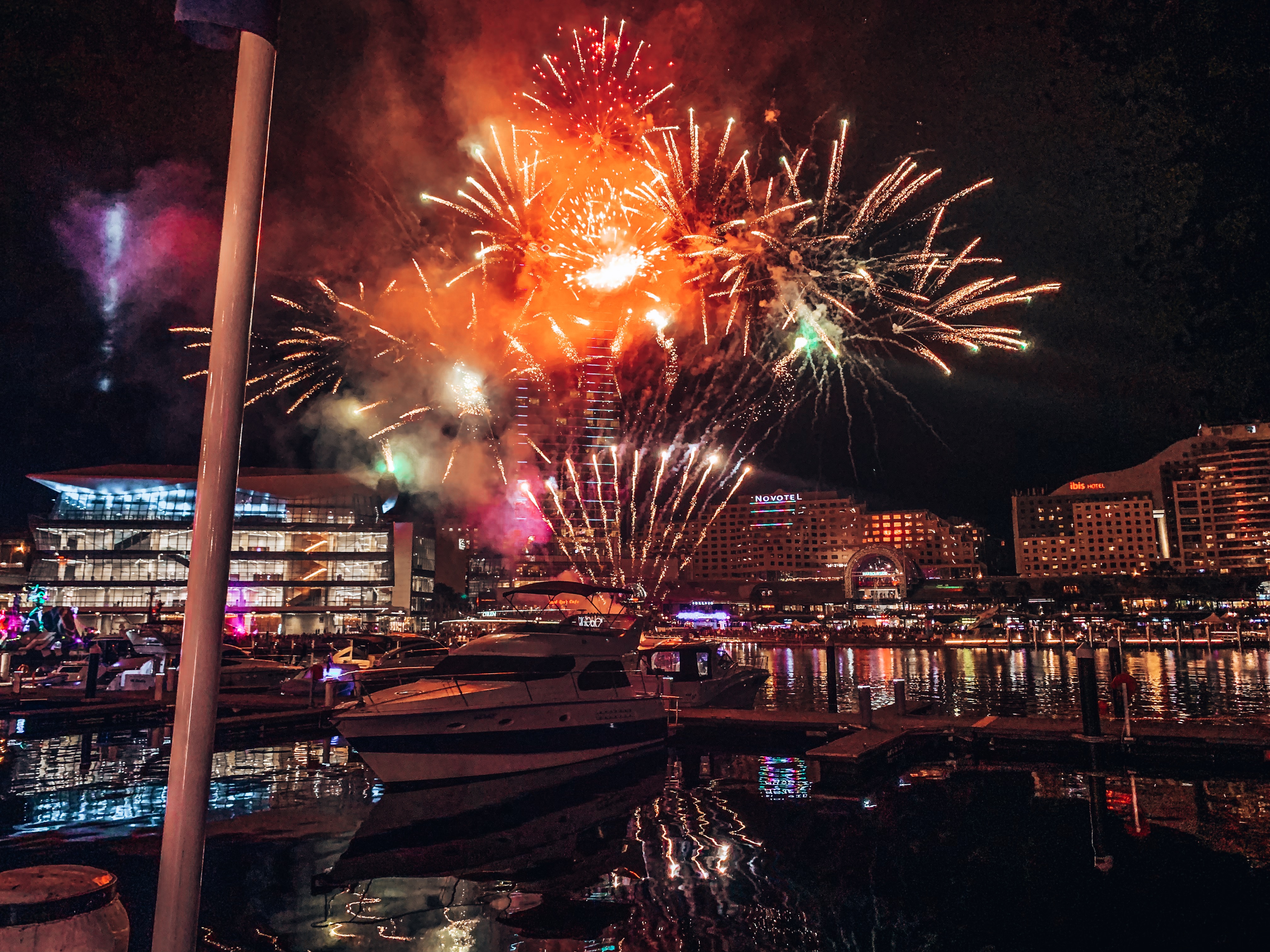 Boat docked on the harbour with fireworks exploding in the background