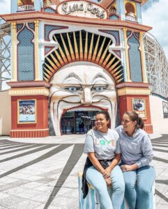 St Kilda Luna Park - Two girls posing outside large clown face entry with mouth as entry - Ultimate Guide To Melbourne